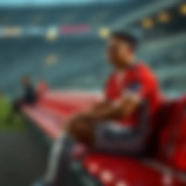 A football player sitting on the bench with a look of contemplation, wearing a team jersey and shorts, during a match, reflecting on the challenges of being labeled a super sub.